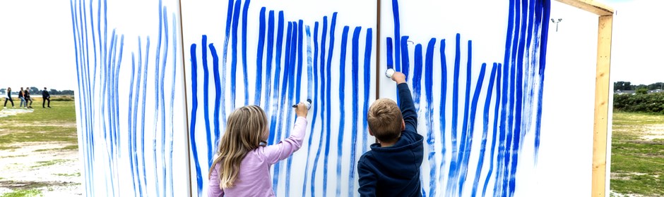 Børn som maler på lærred på stranden