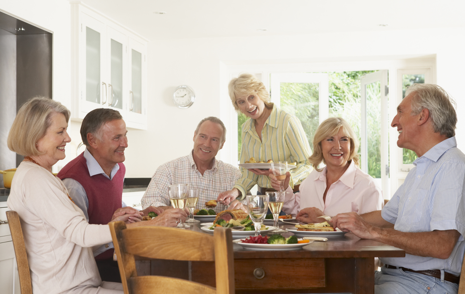 Mennesker der sidder ved bord, spiser og har det sjovt