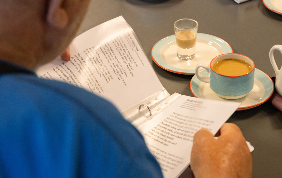 Et bord med en sangbog og kaffe på