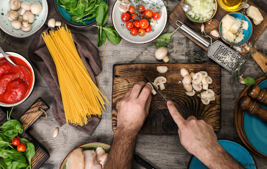 Bord med friske råvare, mand skære svampe