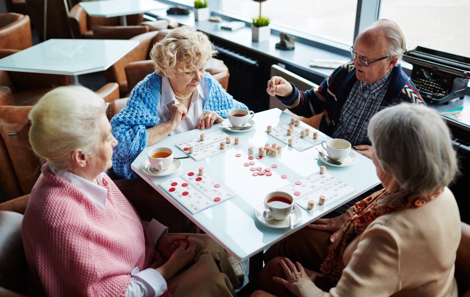 4 mennesker ved et bord, spiller banko og drikker te