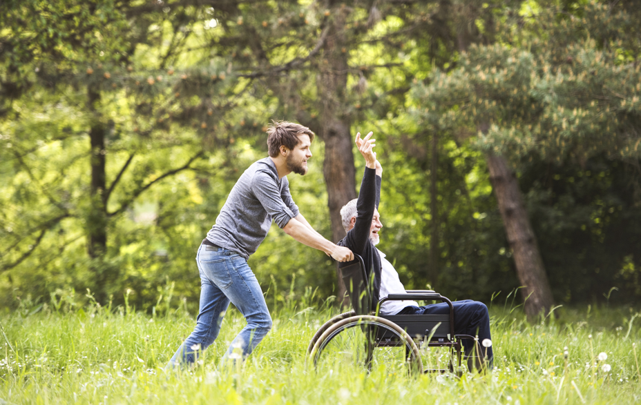 Mand skubber glad mand i kørestol